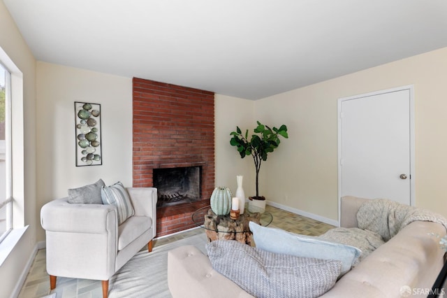 living room featuring a brick fireplace and baseboards