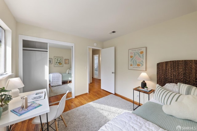 bedroom featuring baseboards, a closet, wood finished floors, and visible vents