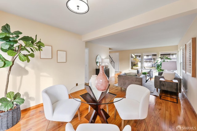 dining space featuring light wood-style floors, baseboards, and stairs