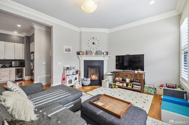 living room featuring ornamental molding, beverage cooler, and light wood-type flooring