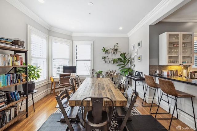 dining room with crown molding, plenty of natural light, and light hardwood / wood-style floors