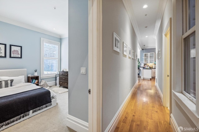 corridor featuring ornamental molding and light hardwood / wood-style floors