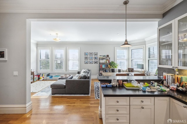 kitchen featuring hanging light fixtures, a wealth of natural light, white cabinets, and light wood-type flooring