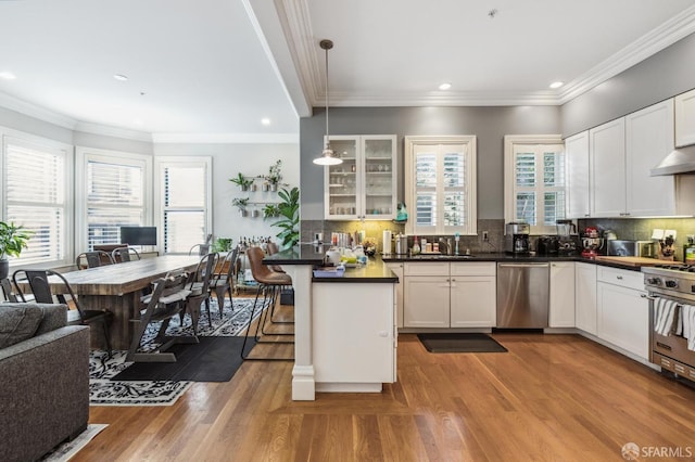 kitchen featuring a breakfast bar, pendant lighting, white cabinets, stainless steel appliances, and a healthy amount of sunlight