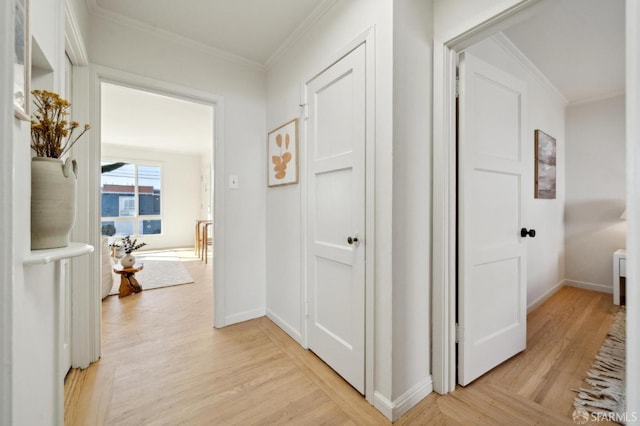 hall with ornamental molding, light wood-style flooring, and baseboards