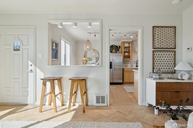 kitchen featuring light countertops, hanging light fixtures, visible vents, brown cabinetry, and stainless steel fridge