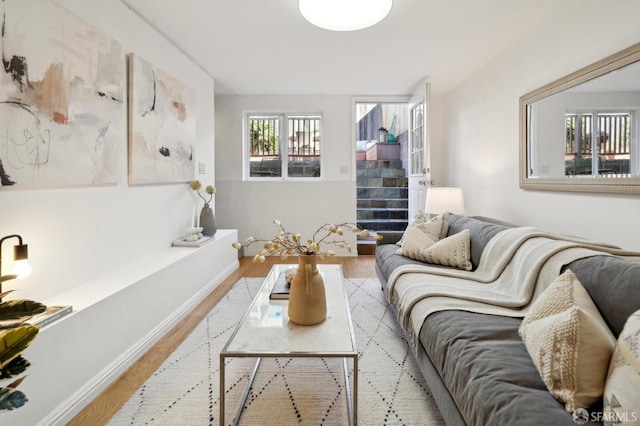 living room with stairs, baseboards, and light wood-style floors