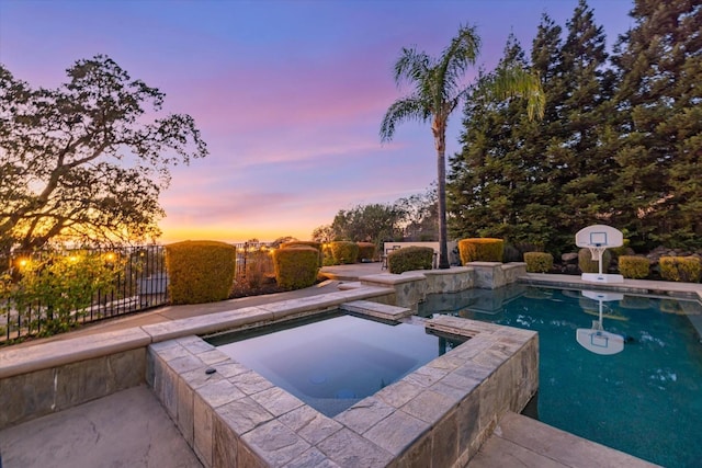 pool at dusk with an in ground hot tub