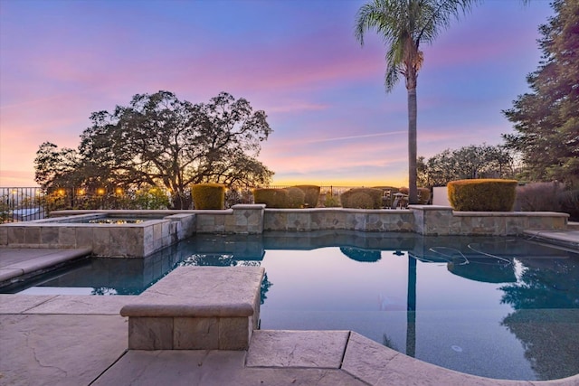 pool at dusk featuring an in ground hot tub