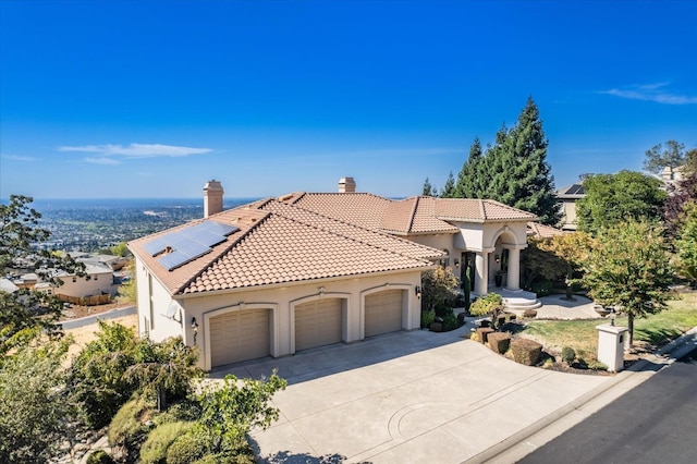 mediterranean / spanish house featuring solar panels and a garage