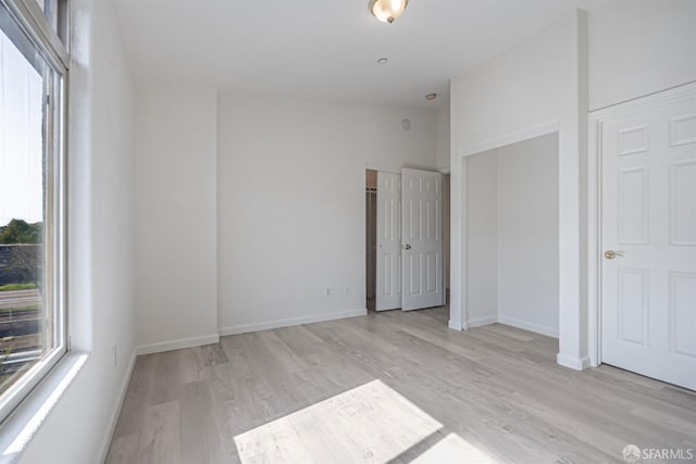 unfurnished bedroom with baseboards, vaulted ceiling, and wood finished floors