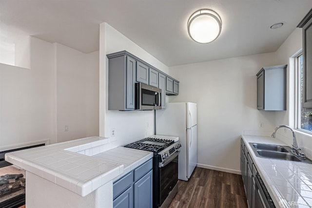 kitchen with tile countertops, range with gas cooktop, a sink, and stainless steel microwave