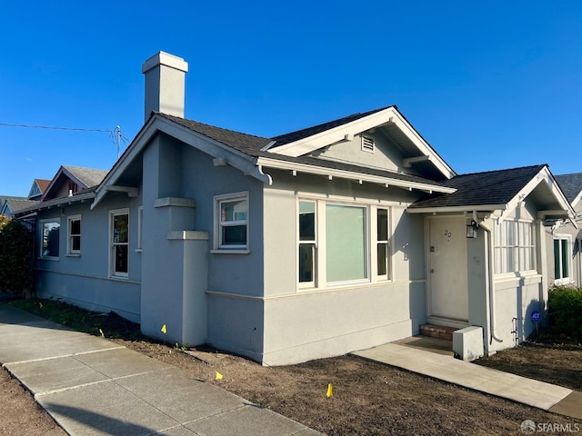 view of front of home featuring entry steps, stucco siding, and a chimney
