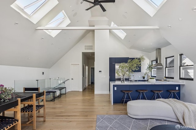 3441 20th St, San Francisco, CA 94110 - living room featuring a skylight, high vaulted ceiling, light wood-style floors, ceiling fan, and plenty of natural light