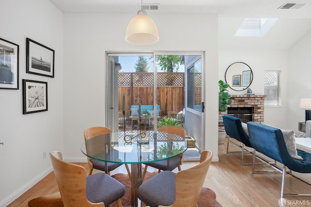 3937 Vine St, Pleasanton, CA 94566 - dining area with light wood-type flooring, a brick fireplace, a skylight, and baseboards