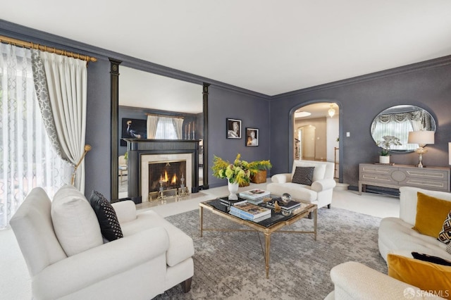 living room featuring carpet floors, arched walkways, a warm lit fireplace, and crown molding