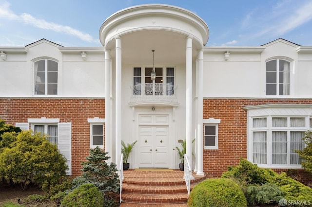 exterior space with brick siding, a balcony, and stucco siding