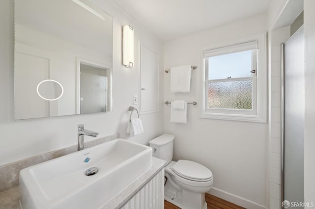 bathroom with baseboards, vanity, toilet, and wood finished floors