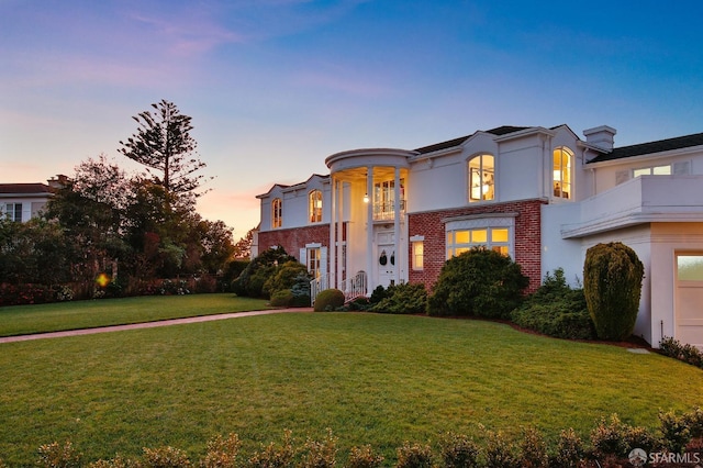 mediterranean / spanish-style house featuring brick siding, a lawn, and stucco siding