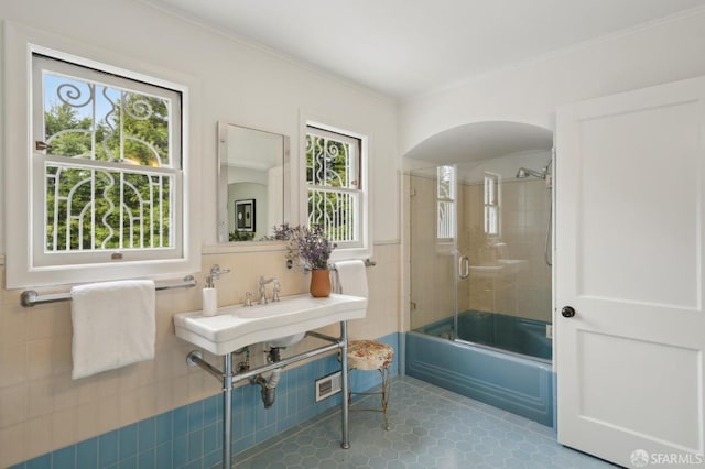 full bathroom featuring bath / shower combo with glass door, plenty of natural light, tile walls, and tile patterned floors