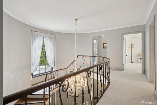 hallway with carpet floors, arched walkways, ornamental molding, and an upstairs landing