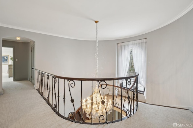 hall with carpet, arched walkways, crown molding, and an upstairs landing