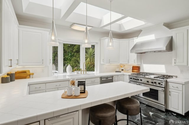 kitchen featuring marble finish floor, appliances with stainless steel finishes, white cabinetry, a sink, and wall chimney range hood