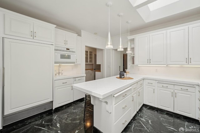 kitchen with marble finish floor, a skylight, and white cabinets