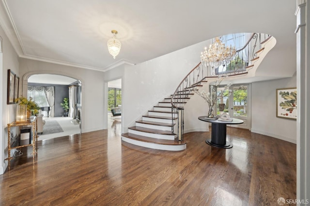 foyer entrance with stairway, arched walkways, a wealth of natural light, and wood finished floors