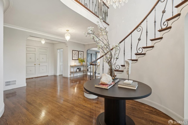 foyer featuring ornamental molding, arched walkways, visible vents, and wood finished floors