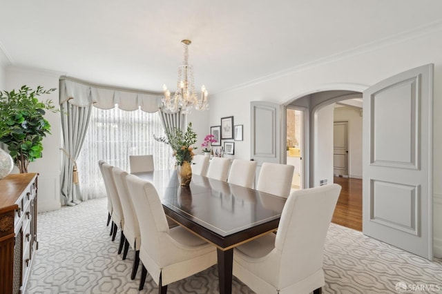 dining space featuring arched walkways, ornamental molding, and a chandelier