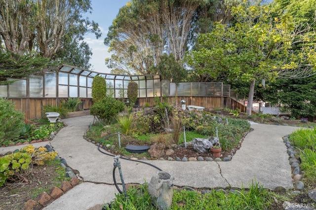 view of yard featuring fence, a greenhouse, and an outdoor structure