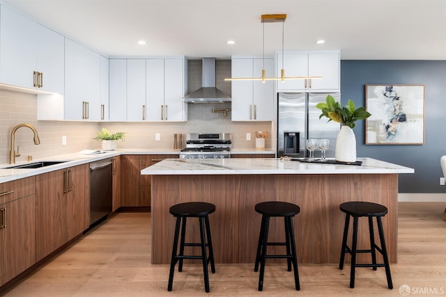 2277 33rd Ave, San Francisco, CA 94116 - kitchen featuring wall chimney exhaust hood, appliances with stainless steel finishes, a breakfast bar, light wood-style flooring, and recessed lighting
