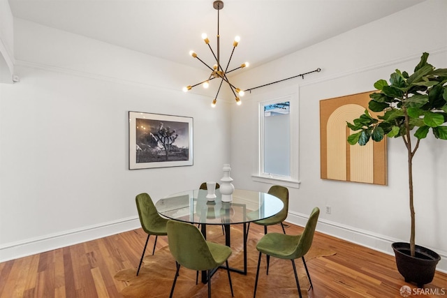 dining space featuring a chandelier, wood finished floors, and baseboards