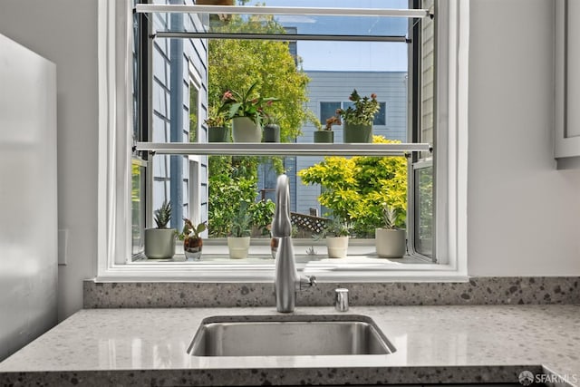 kitchen with a sink, plenty of natural light, and light stone countertops