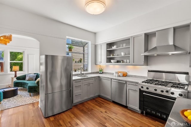 kitchen with appliances with stainless steel finishes, wall chimney exhaust hood, gray cabinets, a sink, and plenty of natural light