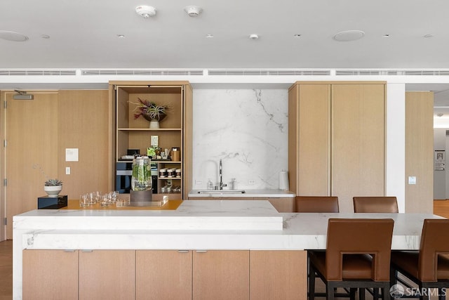 bar with wall oven, light brown cabinets, tasteful backsplash, and sink