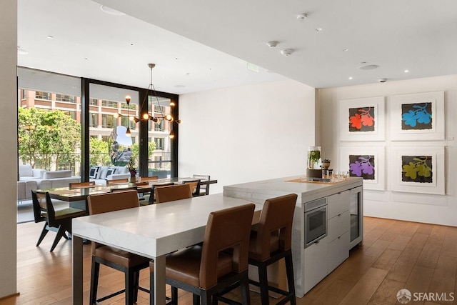 kitchen featuring wood-type flooring, a chandelier, hanging light fixtures, and expansive windows