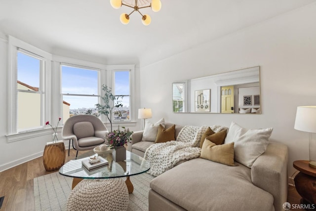 living room with an inviting chandelier, plenty of natural light, baseboards, and wood finished floors