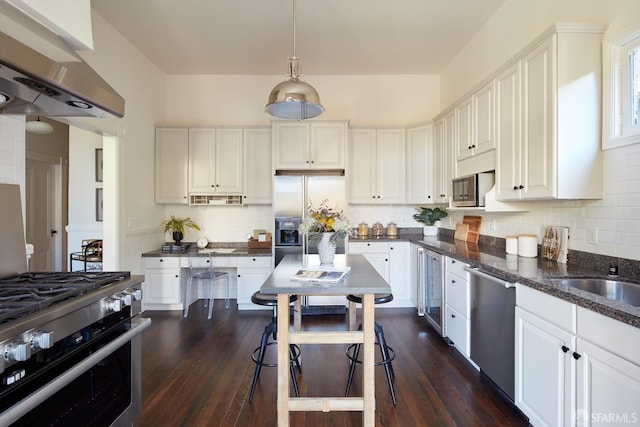 kitchen with range hood, pendant lighting, stainless steel appliances, and white cabinets