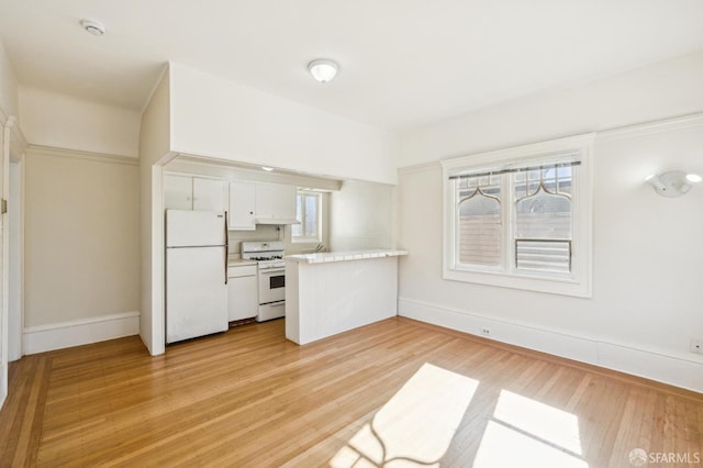 516 Stanyan St, San Francisco, CA 94117 - kitchen featuring white cabinets, light countertops, light wood-type flooring, white appliances, and a peninsula
