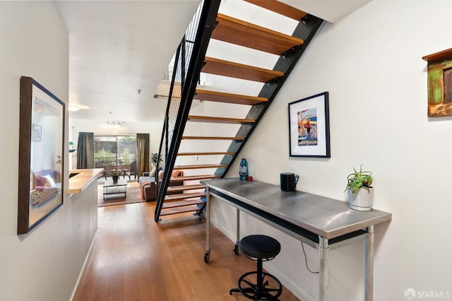 corridor featuring stairway, wood finished floors, and baseboards