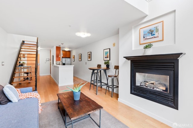 living room featuring light wood finished floors, a glass covered fireplace, and baseboards