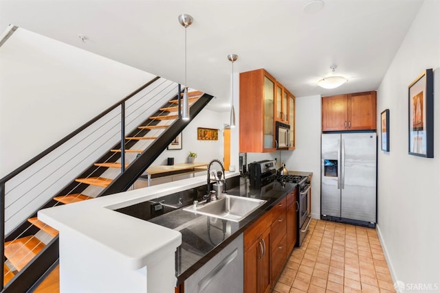 kitchen with appliances with stainless steel finishes, a sink, brown cabinetry, dark countertops, and glass insert cabinets