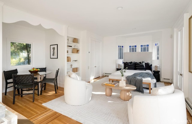 bedroom featuring light wood finished floors, a baseboard radiator, a baseboard heating unit, and baseboard heating