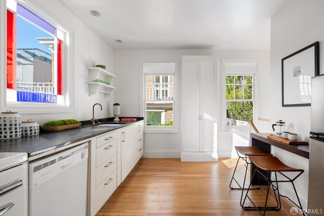 kitchen with a healthy amount of sunlight, white cabinets, white dishwasher, and a sink