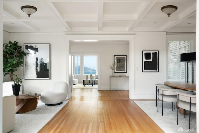 interior space with baseboards, coffered ceiling, beamed ceiling, and light wood finished floors