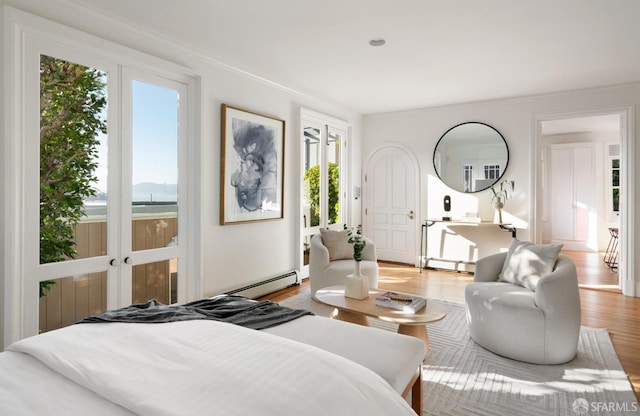 bedroom featuring a baseboard heating unit, ornamental molding, baseboard heating, and wood finished floors