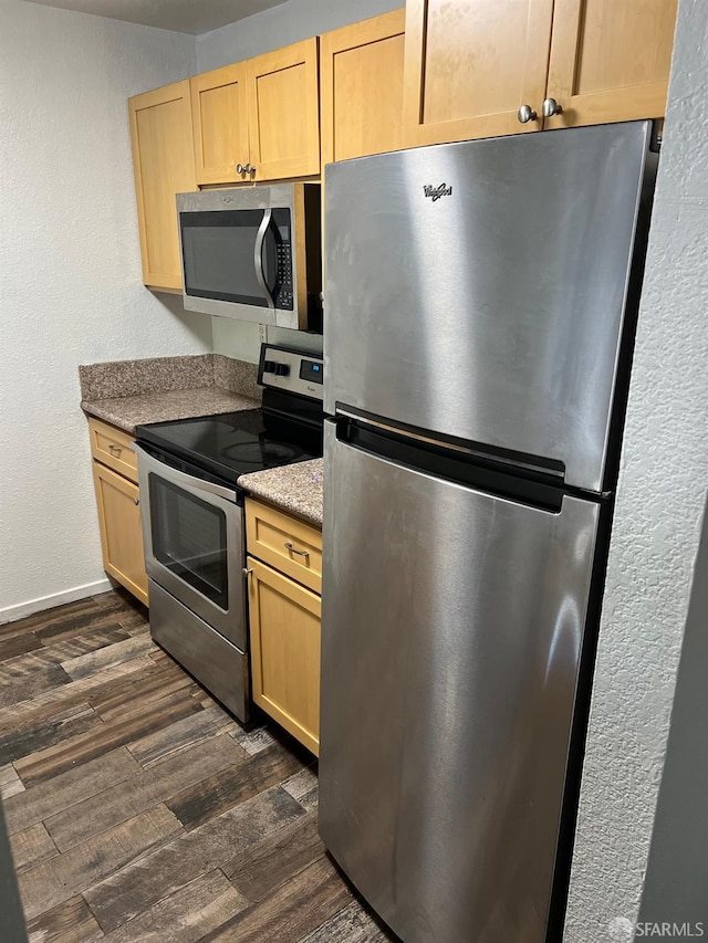 kitchen with appliances with stainless steel finishes, light brown cabinets, and dark hardwood / wood-style flooring