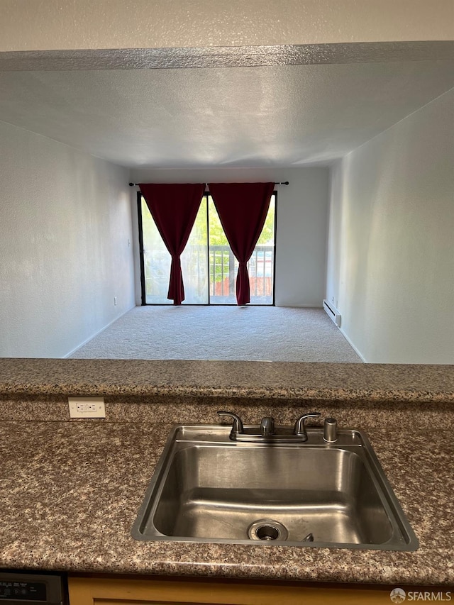 kitchen featuring carpet flooring, dishwashing machine, sink, and a textured ceiling